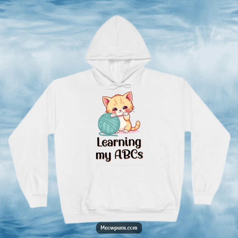 Funny hoodie featuring a playful kitten batting a giant letter-shaped yarn ball, offering warmth and a touch of playful innocence.