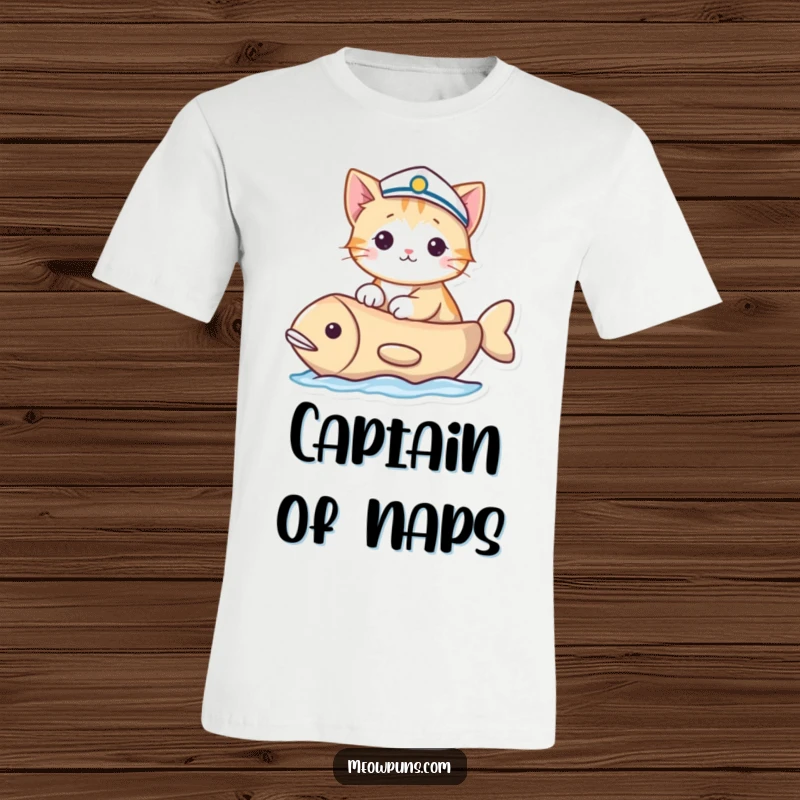Funny T-shirt depicting a cat in a sailor hat sailing a fish-shaped boat, showcasing maritime humor and feline exploration.