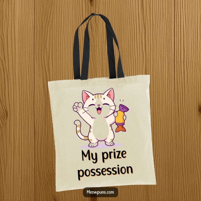 Funny cat tote bag depicting a cute cat in a triumphant pose, proudly holding a toy it just caught, for carrying items.